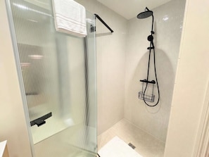 Ein modernes Badezimmer mit einer Duschkabine aus Glas, einer Handbrause und einem Handtuchhalter.