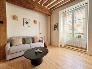 Ein Wohnzimmer mit einer Couch, einem Couchtisch und einem Fenster mit Vorhängen.