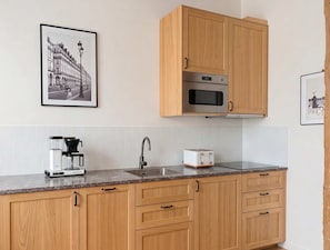 Eine Küche mit Holzausstattung, einer Mikrowelle, einer Kaffeemaschine und einem Toaster auf der Arbeitsfläche.