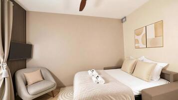 A modern hotel room with a bed, a chair, a ceiling fan, a TV, and abstract wall art.