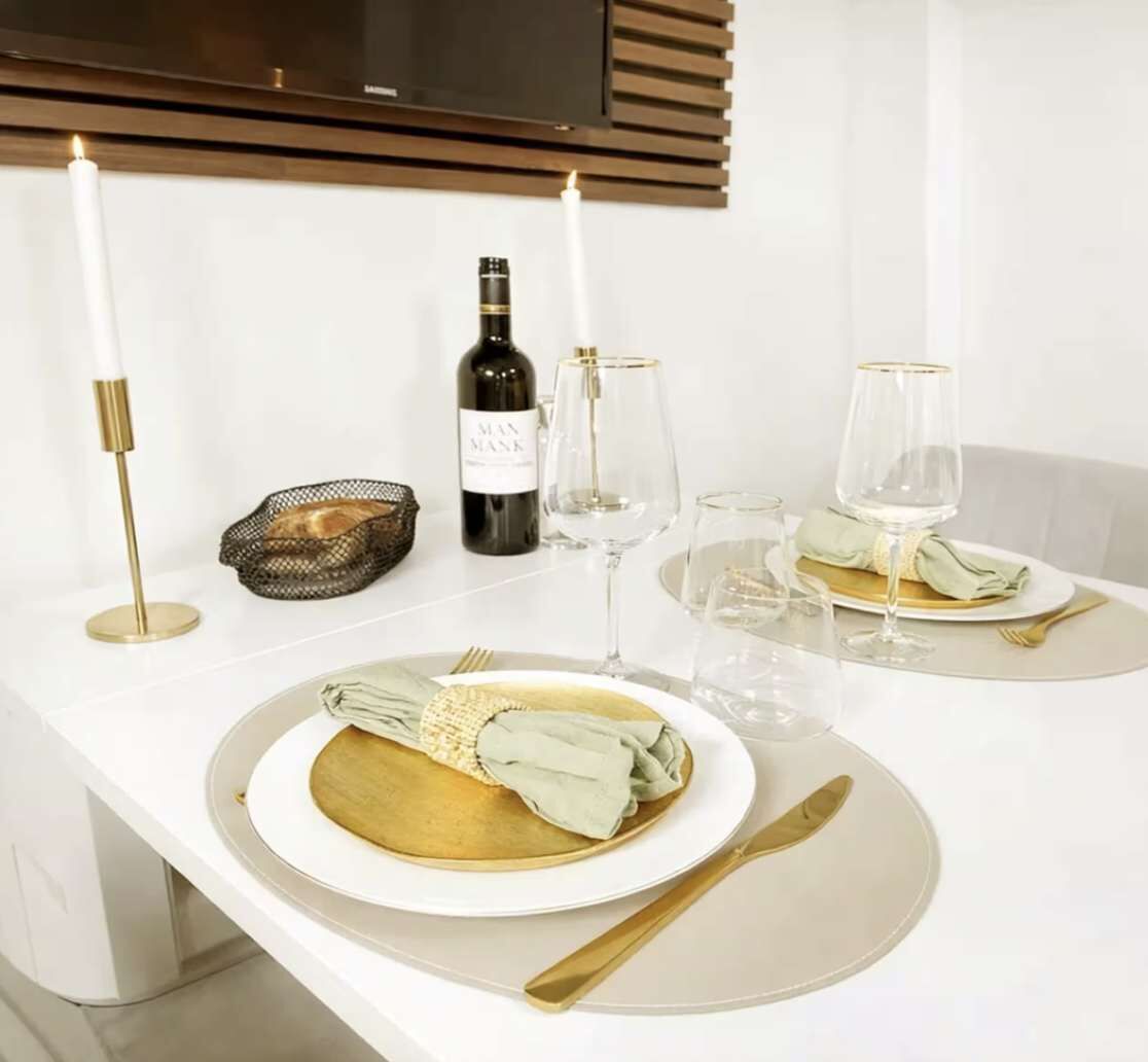 Mesa de comedor servida con platos, vasos, cubiertos y velas, que sugiere un ambiente formal para cenar.