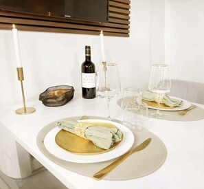 A dining table set with plates, glasses, cutlery, and candles, suggesting a formal dining arrangement. - Cozy Studio - Marais, Louvre by Melvane (Paris)