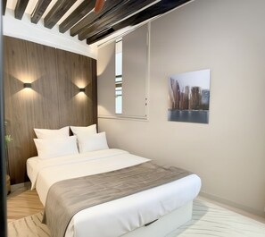 Ein modernes Schlafzimmer mit einem Bett, einer Holzpaneelwand, zwei Wandleuchten, einem Fenster und einem gerahmten Bild.