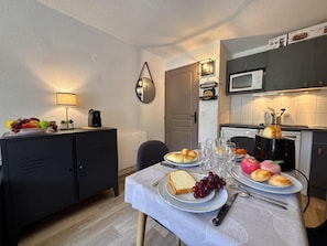 A dining area with a table set for two, a microwave, and a cabinet with a fruit bowl. - 100m from ski slopes, 6th floor, balcony, tv, ski locker, 27m², Vars (Vars)