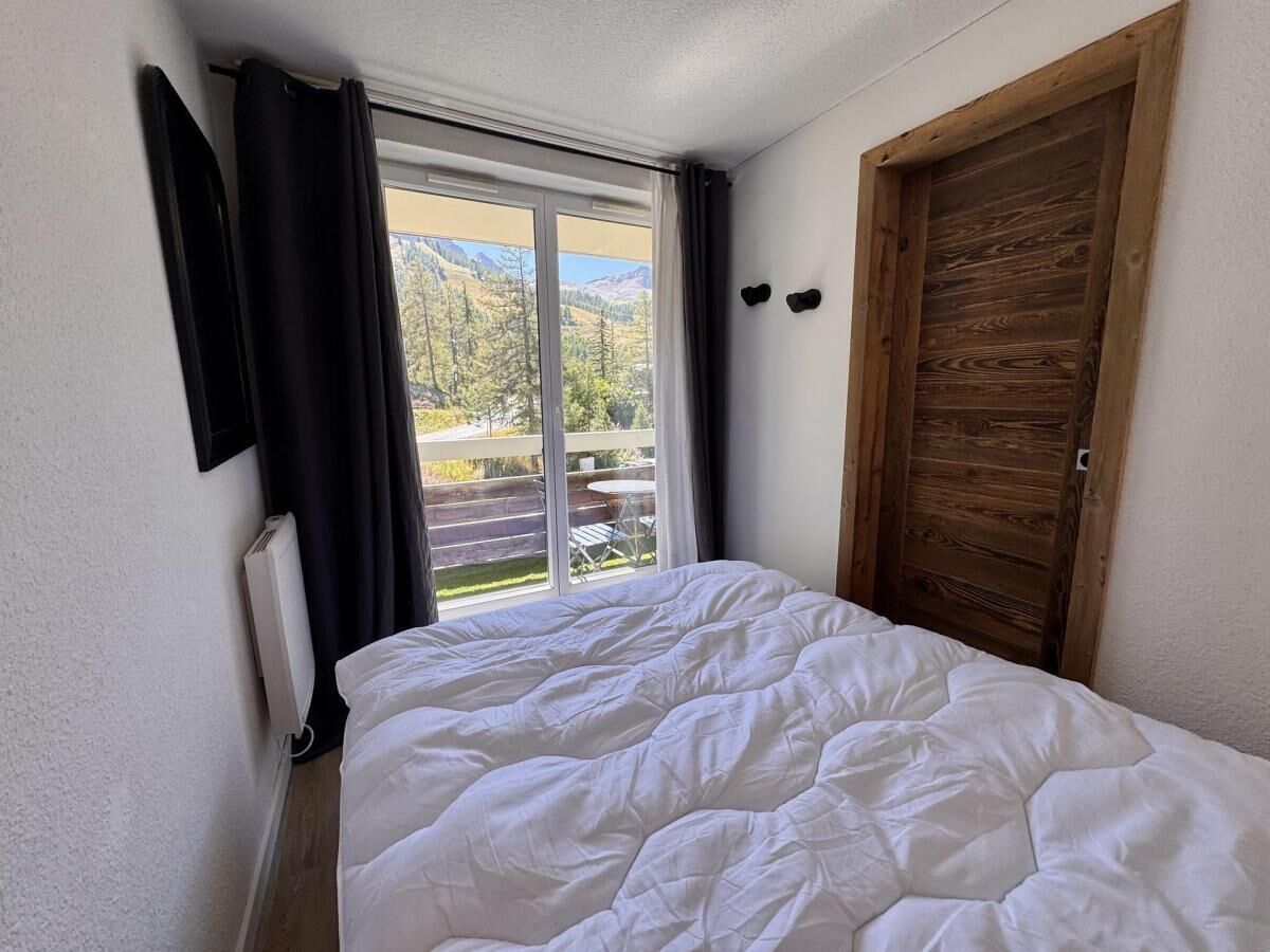 Een slaapkamer met een bed, een raam en uitzicht op een terras.