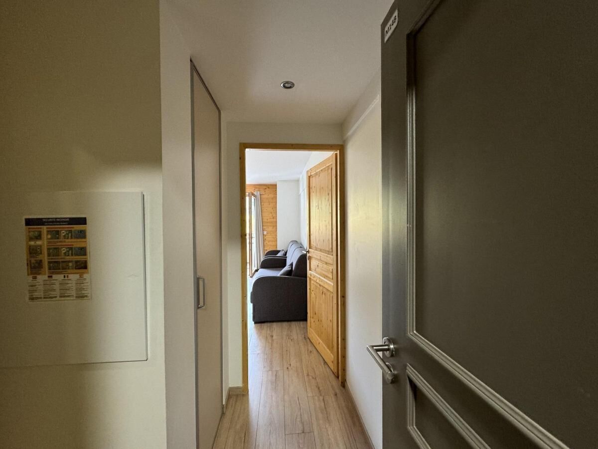 Un passadís que condueix a una habitació amb un llit i una porta de fusta.