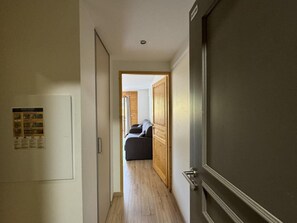 A hallway leading to a room with a bed and a wooden door. - 50m from ski slopes, 1st floor, swimming pool, balcony, ski locker, 30m², Vars (Vars)
