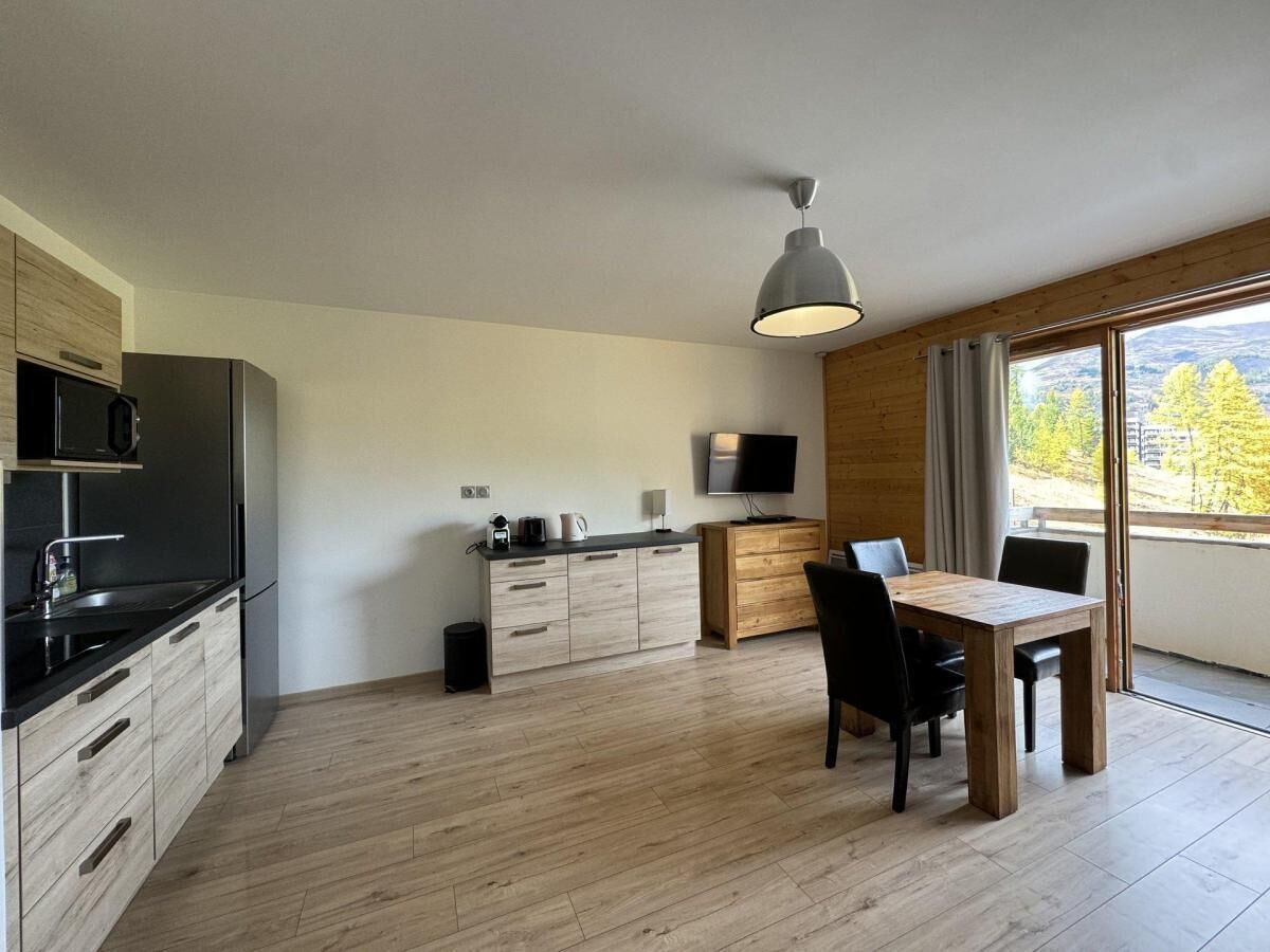 Une cuisine moderne avec un coin repas, des meubles en bois et une grande fenêtre.