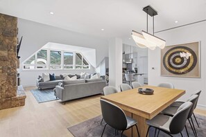 A modern living space with a dining area, a grey sofa, and a large window offering a view of the outdoors. - Solaris PHFW - 3 Bedroom + Den (Vail)