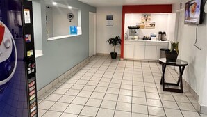 En hotellobby med en automattankstation, en krukväxt, en kaffemaskin och en tv på väggen.