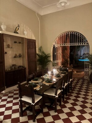 A dining area with a checkered floor, a long table set for six, and a decorative archway. - Historic Waterfront Villa with Dock, Private Pool and Caribbean Charm (Cartagena)