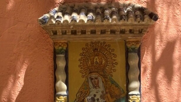 Eine Wandplatte mit einer religiösen Figur, einem aufwendigen Rahmen und einem Ziegeldach.