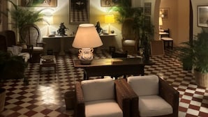 Eine Hotelhalle mit Schachbrettboden, Gewölbedecke und einer zentralen Sitzecke mit Lampen.