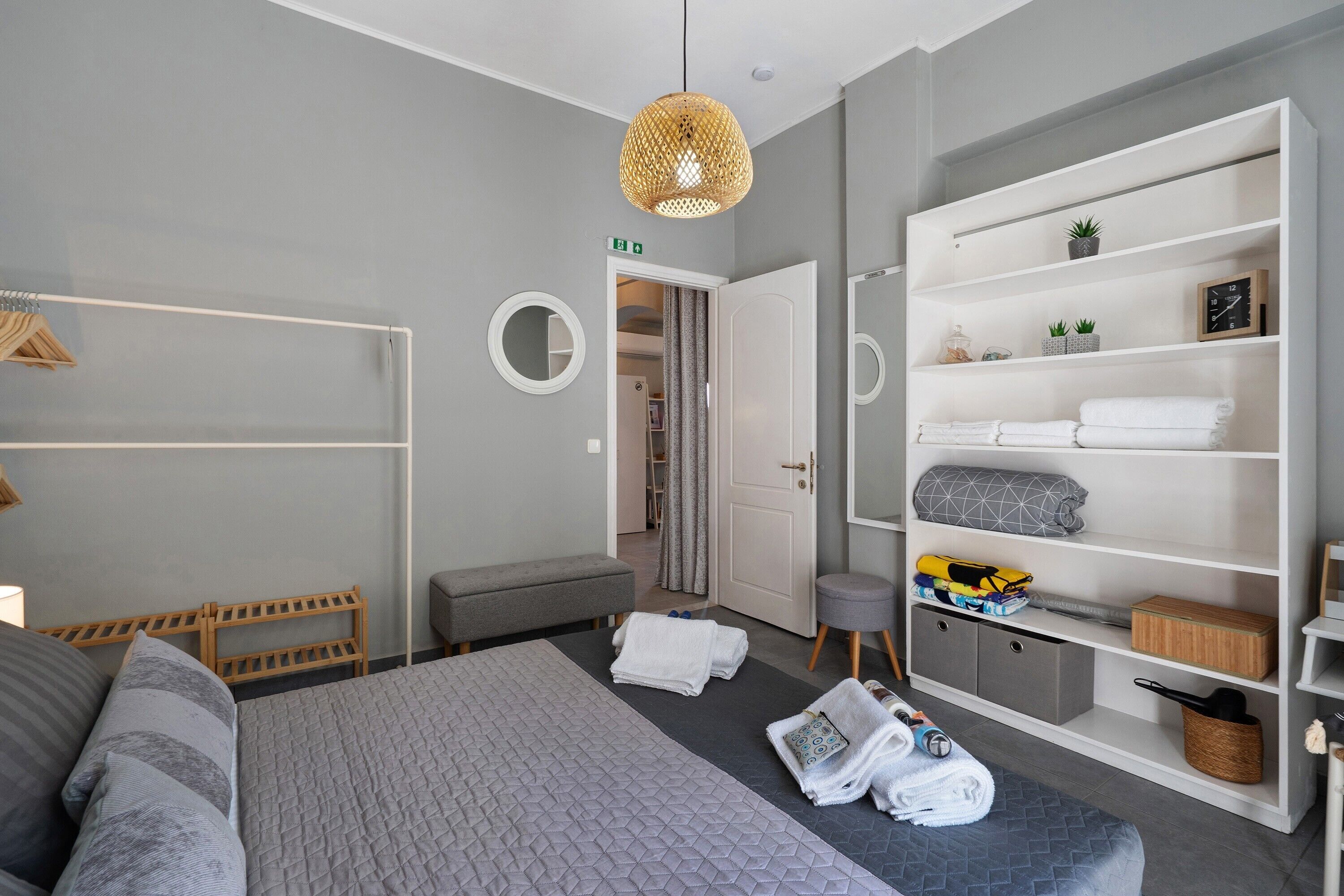 Een moderne slaapkamer met een bed, een kast, een bankje en een klein krukje.