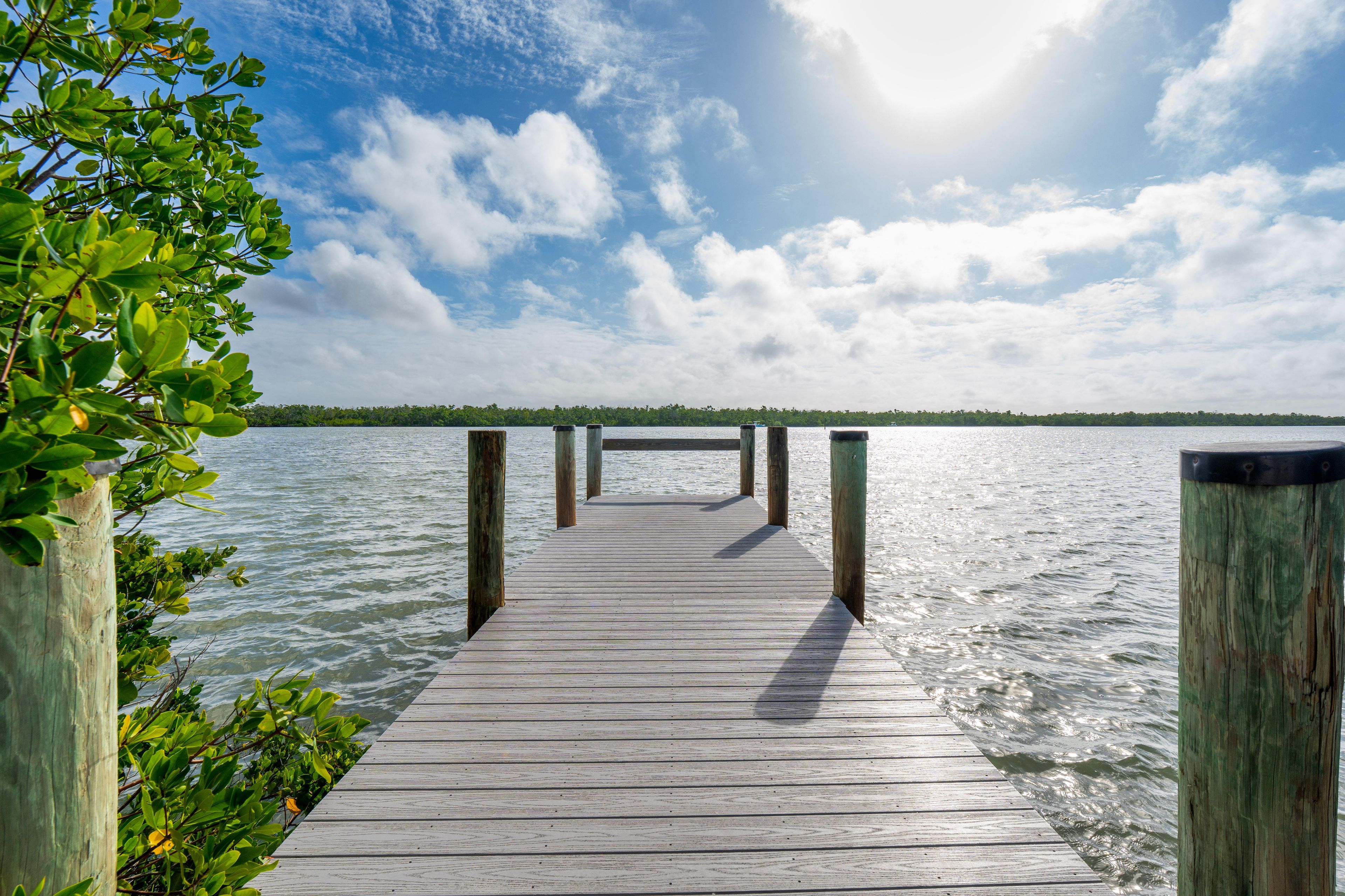 A wooden pier extending into calm water with a clear sky above.