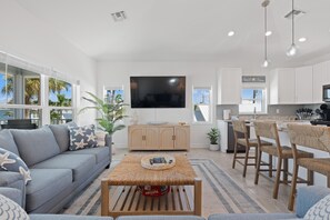 A modern living room with a grey sofa, a coffee table, and a TV mounted on the wall. - Pearl Street Retreat (Fort Myers Beach)