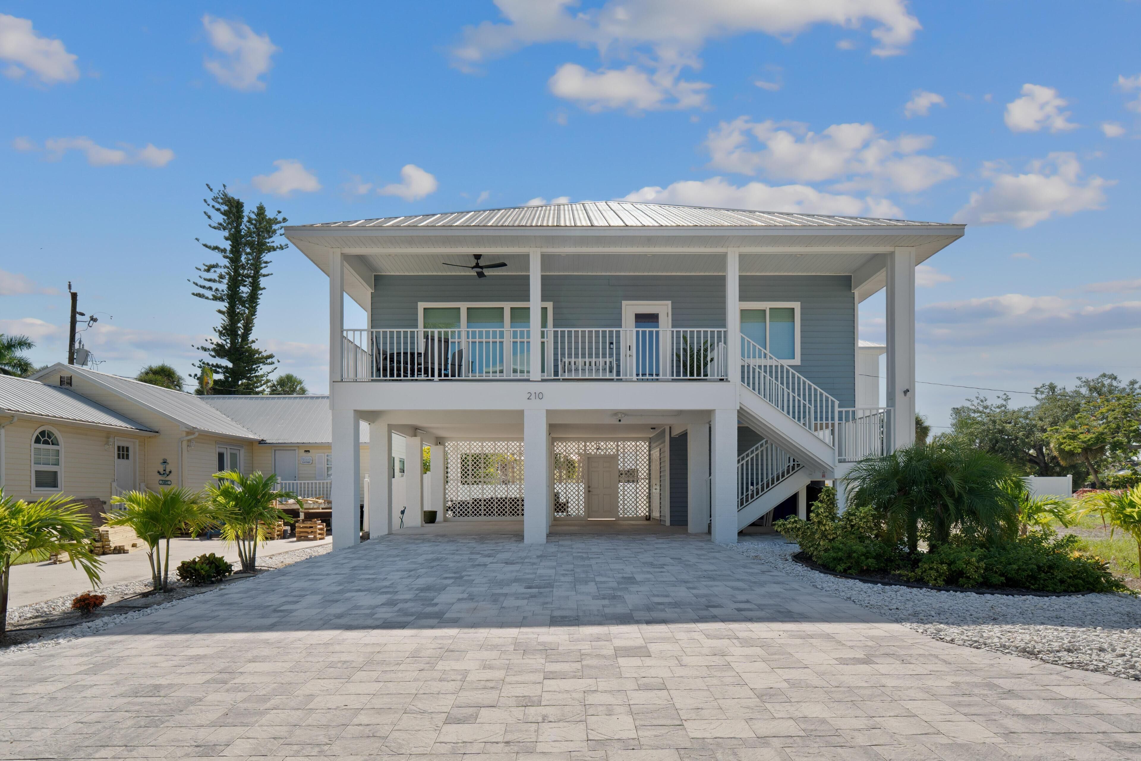 A two-story beachfront property with a covered patio, a balcony, and a staircase leading to the upper level.