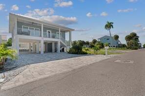 A two-story house with a covered porch and a staircase leading to the upper floor. - Pearl Street Retreat (Fort Myers Beach)