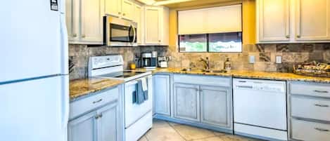A kitchen with white cabinets, a microwave, a stove, and a dishwasher.
