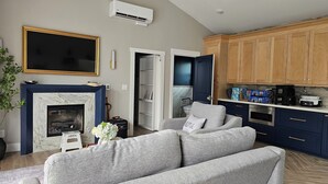 A living room with a fireplace, a sofa, and a kitchen area with wooden cabinets and appliances.
