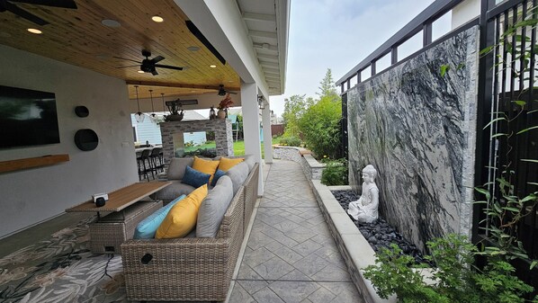 Un patio exterior con un sofá, una mesa y un ventilador de techo.