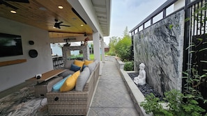 An outdoor patio with a sofa, a table, and a ceiling fan.