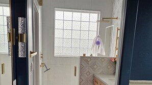 A modern bathroom with a white sink, a window, and a patterned rug.
