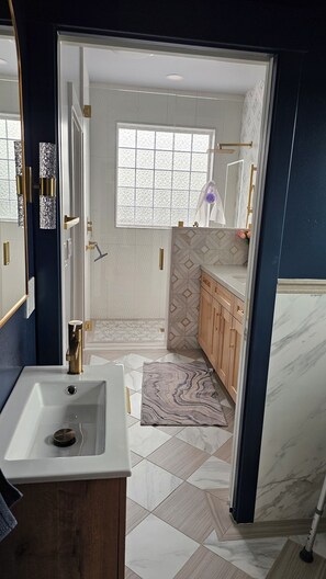 A modern bathroom with a white sink, a window, and a patterned rug.