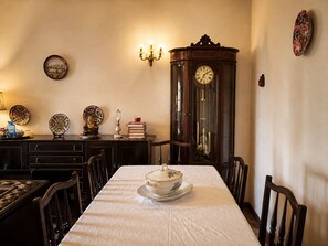 A dining room with a long table, chairs, a clock, wall sconces, and decorative plates. - Pogido Pet House (Arcos de Valdevez)