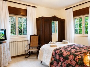 A bedroom with a bed, a chair, a wooden wardrobe, a radiator, and a television. - Pogido Pet House (Arcos de Valdevez)