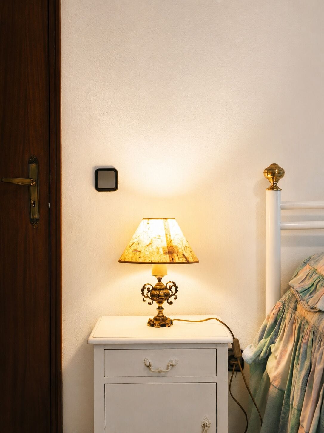 Et natbord med lampe, stikkontakt og en dør.