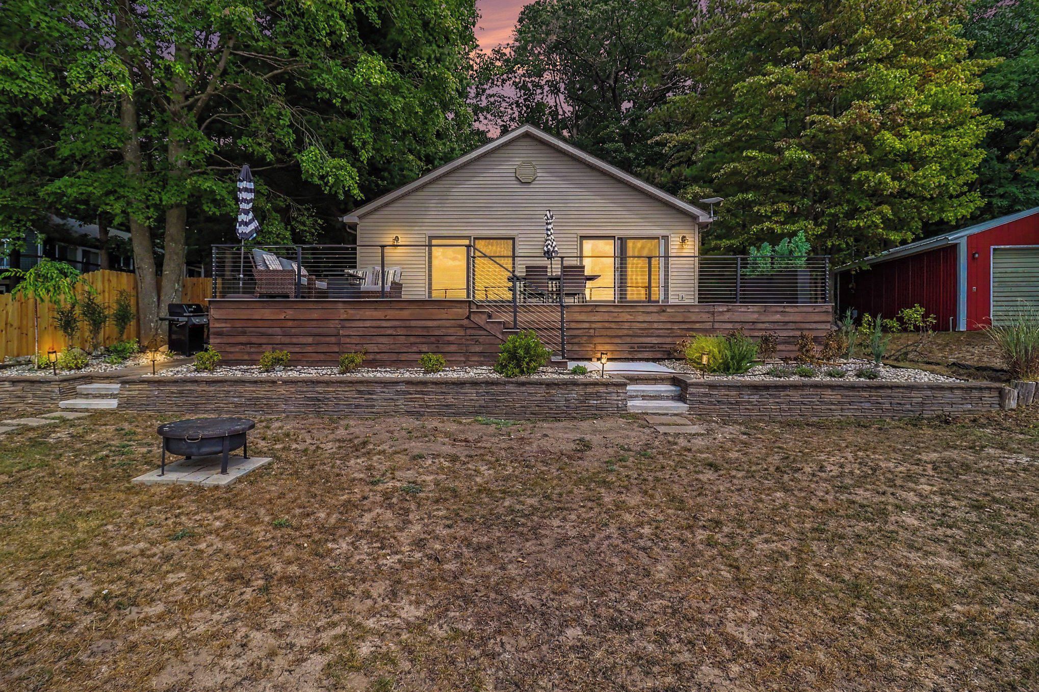 Una casa de dos pisos con un patio techado, una parrilla y un jardín pequeño.