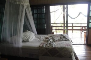 Una cama con dosel, una ventana con cortinas y vistas al exterior.