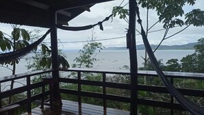 A wooden deck with a view of a body of water and surrounding vegetation. - Pacífic Corcovado Bumgalows - Deluxe Double or Twin Room with Ocean View (Agujitas (Drake))