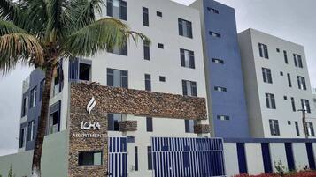A multi-story building with a stone facade, a gated entrance, and a palm tree in the foreground.