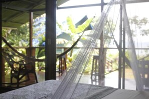 Una hamaca colgada entre dos estructuras, con vistas a muebles de exterior y follaje.