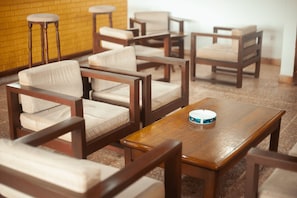 A room with multiple wooden chairs and a table, a brick wall, and a tiled floor.