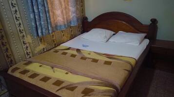A bed with a wooden headboard, white pillows, and a patterned bedspread.