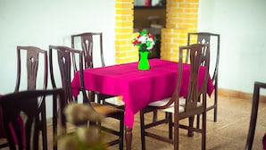 A dining table with a pink tablecloth, surrounded by wooden chairs. - Hôtel Belle Vue Yaounde (Yaoundé)