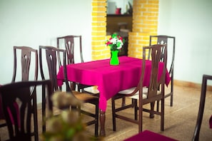 A dining table with a pink tablecloth, surrounded by wooden chairs. - Hôtel Belle Vue Yaounde (Yaoundé)