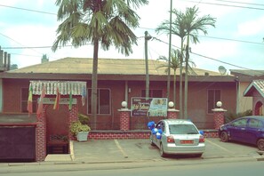 A building with a red brick facade, a signboard, and a parked car with blue balloons.