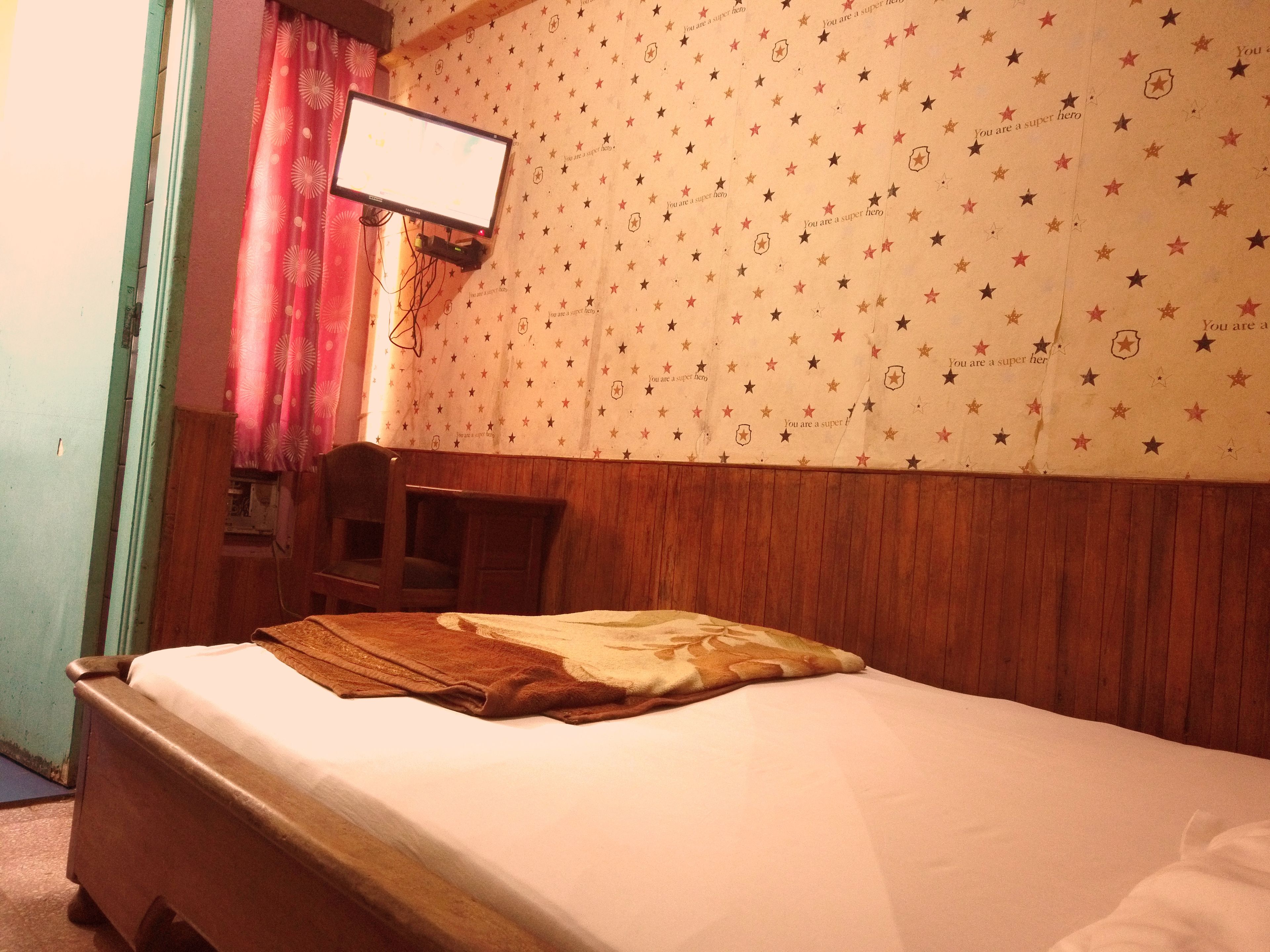 Una habitación con cama, escritorio y televisor de pared.