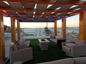 An outdoor seating area with wicker furniture and a view of the sea. - Whale Hill Great View House (Puerto Peñasco)