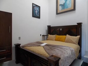 A bedroom with a wooden bed, a nightstand, a wardrobe, and two framed pictures on the wall. - Whale Hill Great View House (Puerto Peñasco)