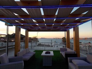 An outdoor seating area with a view of the sea, covered by a wooden pergola with blue LED lights. - Whale Hill Great View House (Puerto Peñasco)