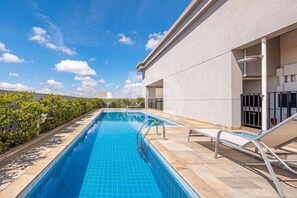 A swimming pool with a tiled edge, a metal handrail, and a lounge chair. - Osasco Trade Fundação (Osasco)