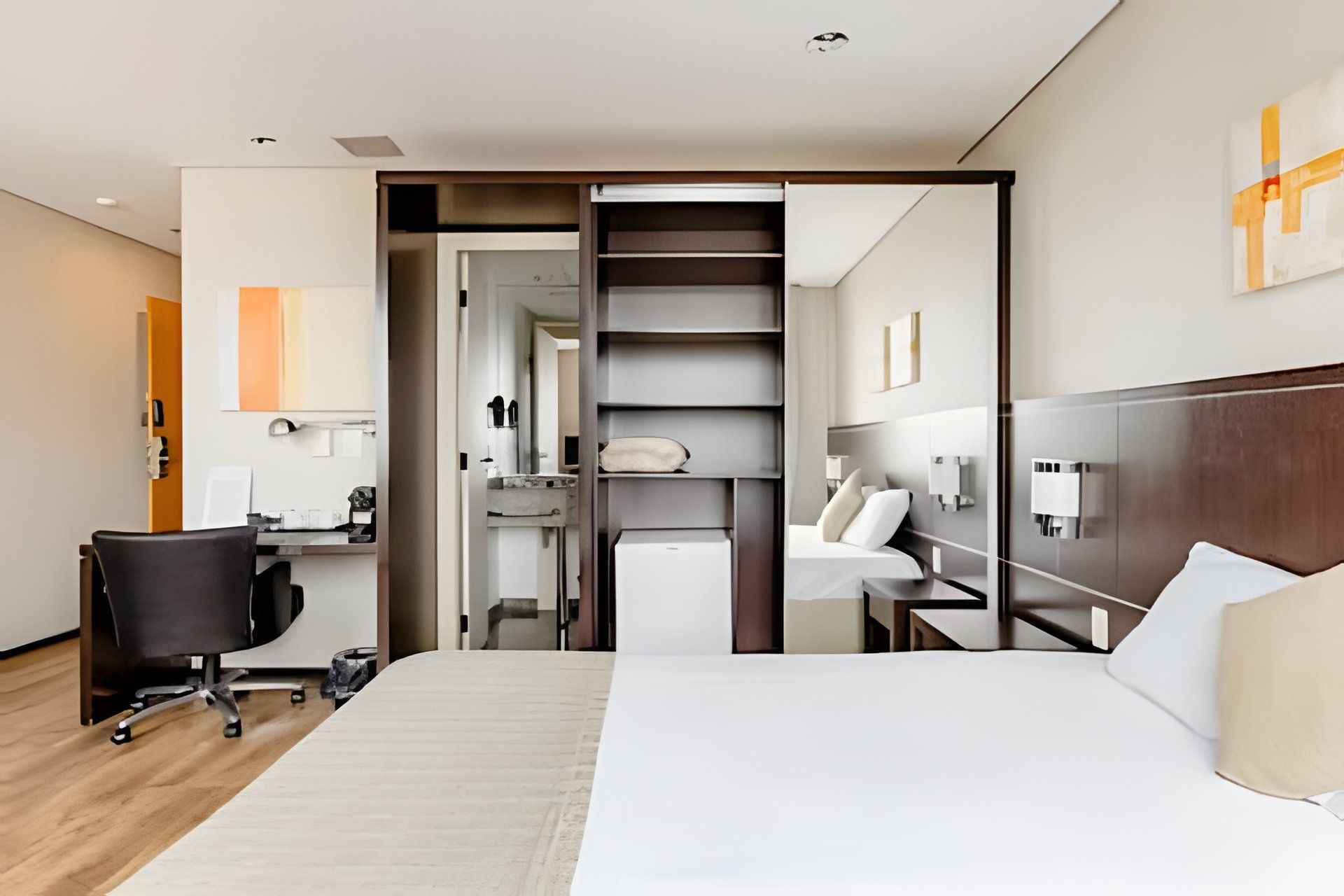 Een moderne hotelkamer met een groot bed, een bureau, een stoel, een kledingkast en een badkamer.