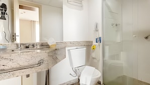 A bathroom with a marble countertop, a glass shower enclosure, and a white toilet. - Osasco Trade Fundação (Osasco)