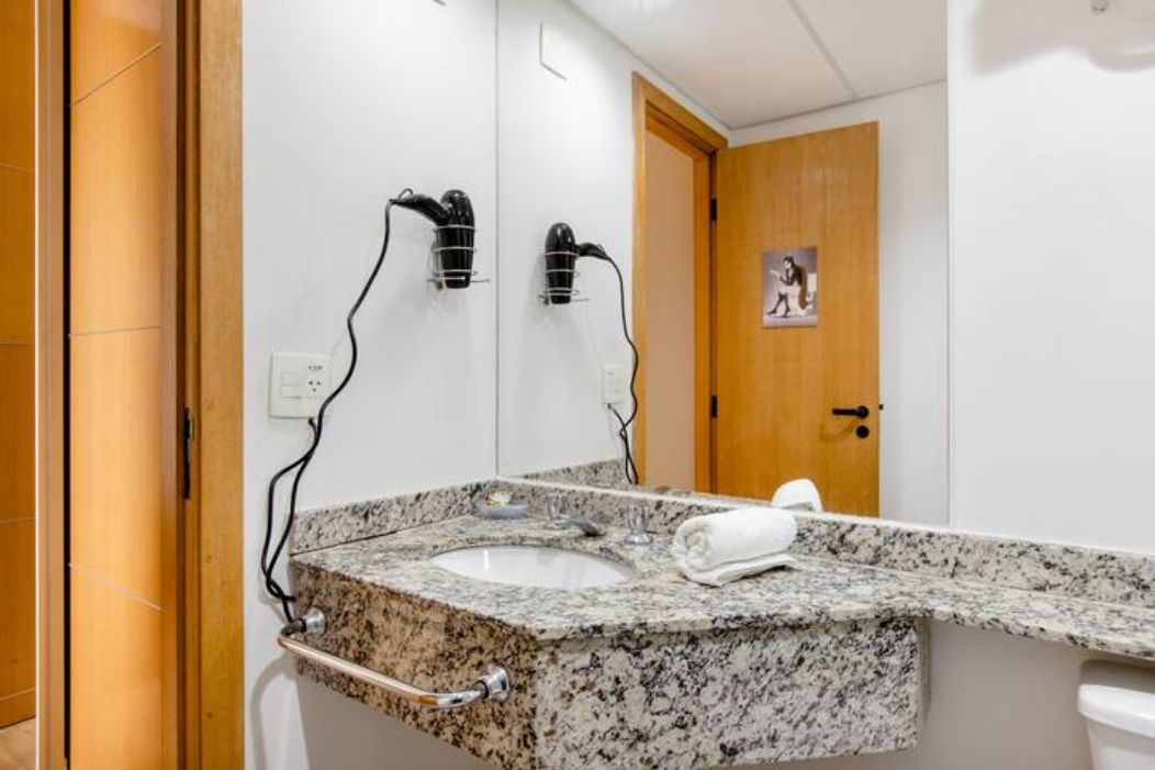 A bathroom with a granite countertop sink, a towel rack, and a door with a poster.