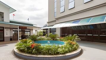 A courtyard with a central pool surrounded by greenery and a tiled floor.